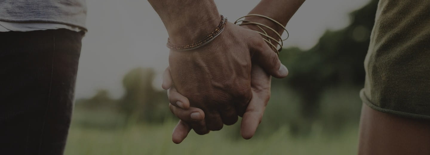 Deux mains qui s’entrelacent délicatement, sur un fond neutre – symbole d’attention et de contact.