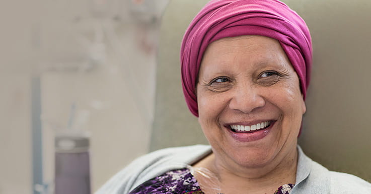 Lächelnde Krebspatientin mit Kopftuch