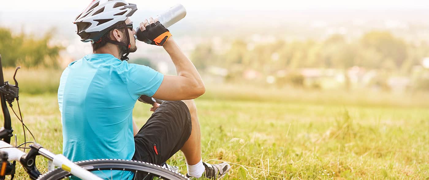 Un ciclista dopo una sessione di allenamento beve dell’acqua seguendo le regole della corretta idratazione