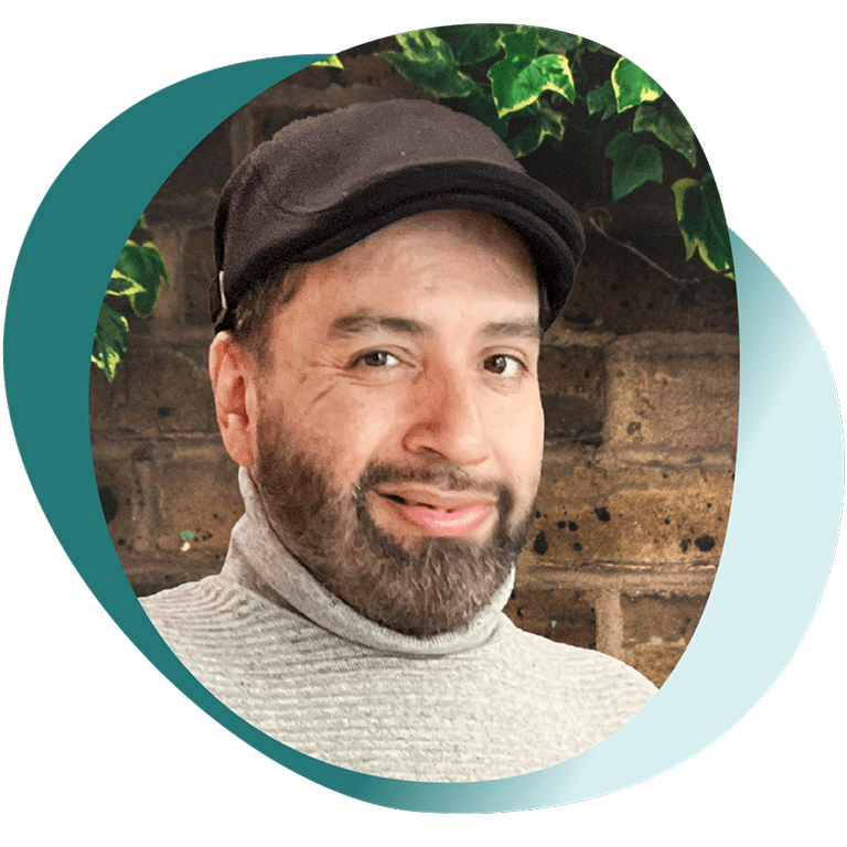 Portrait of Jimmy, a person living with GPP, smiling with a green and brick background